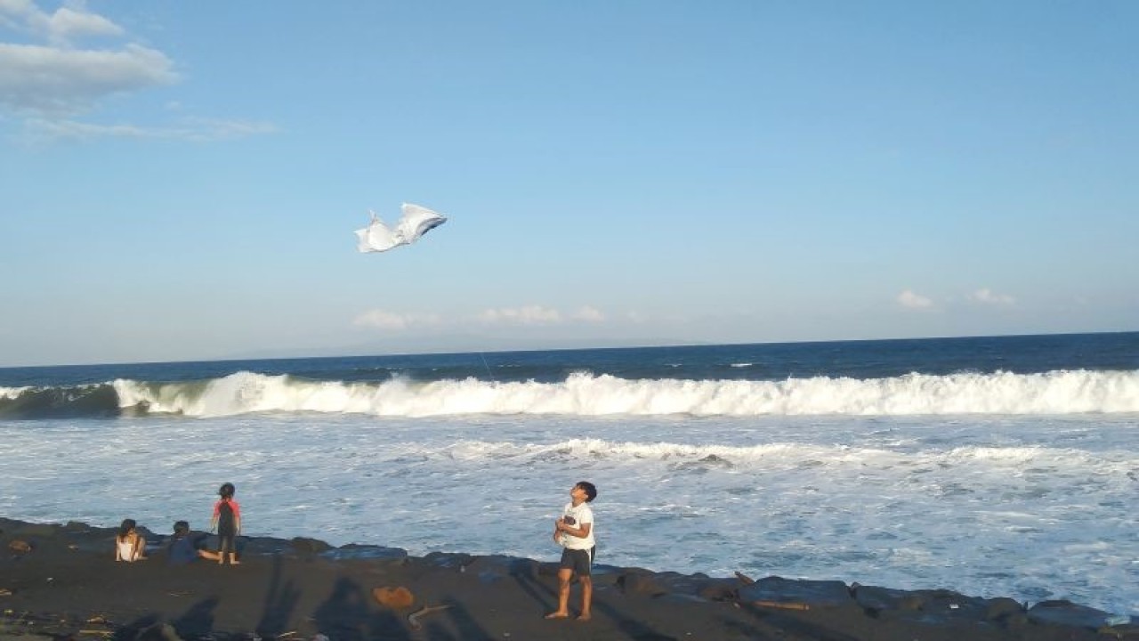 Arsip foto - Seorang anak bermain layangan dengan latar belakang ombak tinggi dan angin kencang di Pantai Purnama, Kabupaten Gianyar, Bali, Minggu (14/5/2023) ANTARA/Dewa Ketut Sudiarta Wiguna