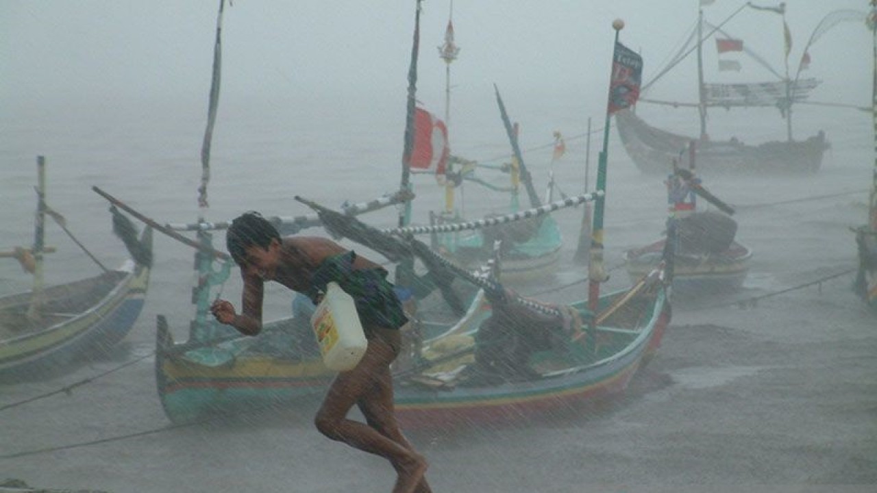 Seorang nelayan berlari meninggalkan perahu yang diguyur hujan deras disertai angin kencang di Pantai Lekok Kabupaten Pasuruan, Jawa Timur, Jumat (4/1). FOTO ANTARA/Musyawir/ss/mes/pri.