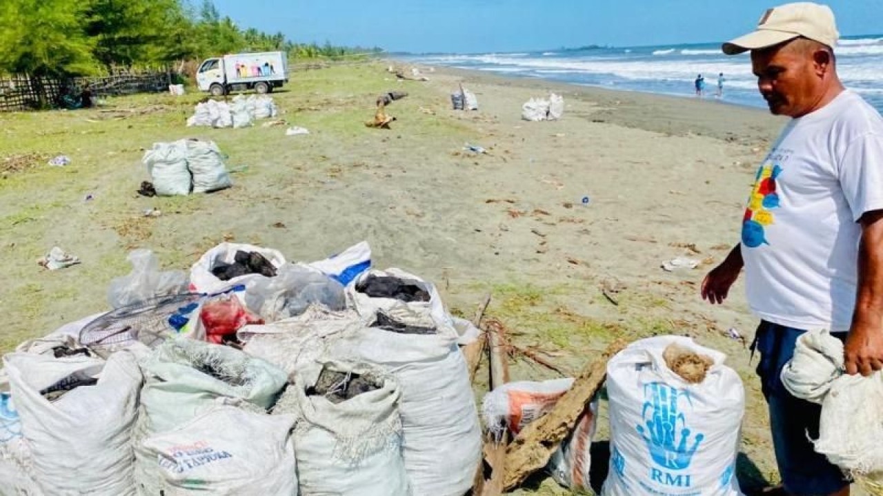 Warga mengumpulkan batu bara yang mencemari kawasan pesisir pantai di Desa Peunaga Pasi, Meureubo, Aceh Barat, Aceh, Selasa (30/5/2023). (ANTARA/Teuku Dedi Iskandar)