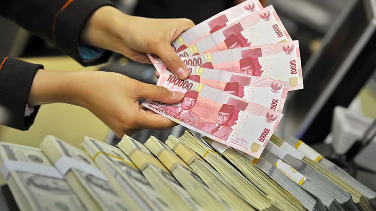 Petugas menunjukkan mata uang rupiah dan dolar AS di Kantor Pusat BNI, Jakarta, Senin (16/12). Nilai tukar rupiah terhadap dolar AS berada pada level Rp12.120/USD seiring tergerusnya Indeks Harga Saham Gabungan (IHSG) pada akhir sesi I perdagangan, namun masih terdepresiasi dibanding penutupan Jumat (13/12) pada level Rp12.106 per dolar AS. ANTARA FOTO/Yudhi Mahatma/ss/ama.