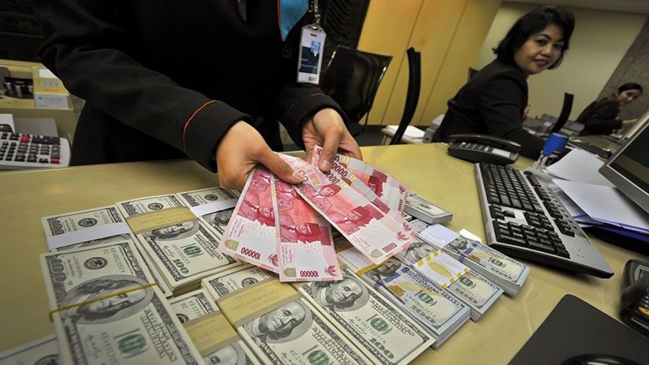 Petugas menunjukkan mata uang rupiah dan dolar AS di Kantor Pusat BNI, Jakarta, Senin (16/12). Nilai tukar rupiah terhadap dolar AS berada pada level Rp12.120/USD seiring tergerusnya Indeks Harga Saham Gabungan (IHSG) pada akhir sesi I perdagangan, namun masih terdepresiasi dibanding penutupan Jumat (13/12) pada level Rp12.106 per dolar AS. ANTARA FOTO/Yudhi Mahatma/ss/ama