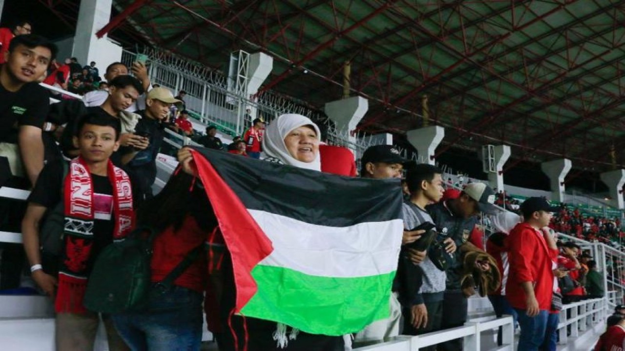 Wakil Ketua DPRD Surabaya Reni Astuti membentangkan bendera Palestina dari tribun Stadion Gelora Bung Tomo (GBT) saat pertandaningan Timnas Indonesia melawan Palestina pada Rabu (14/6/malam. (ANTARA/HO-DPRD Surabaya)