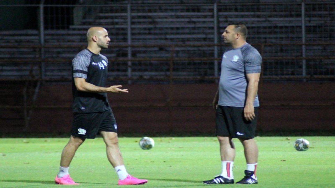 Pemain Timnas Palestina Mohammed Rashid berbincang dengan salah seorang tim pelatih saat latihan perdana di Stadion Gelora 10 November Surabaya, Minggu (11/6/2023) malam. (ANTARA/Naufal Ammar Imaduddin)