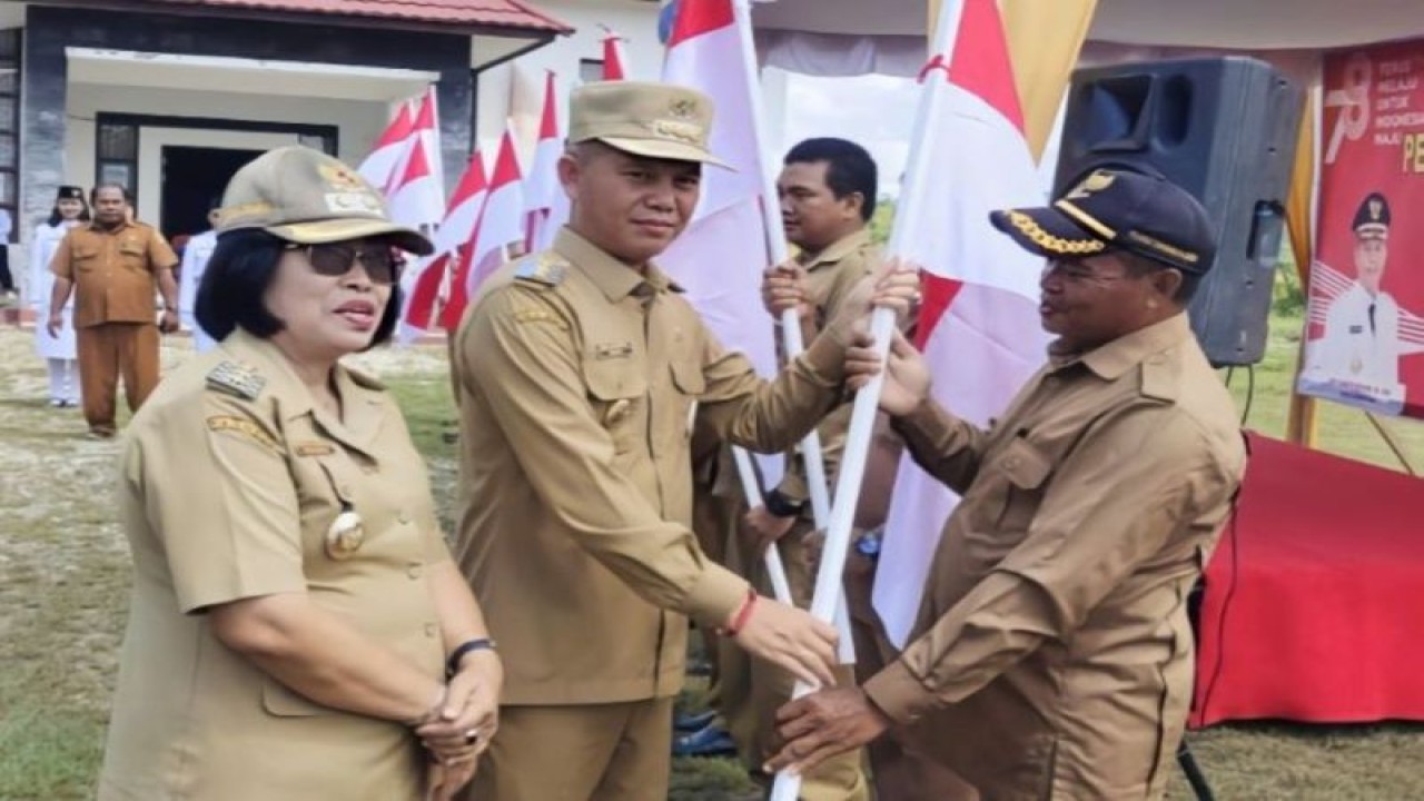 Bupati Gunung Mas Jaya S Monong (dua kiri) didampingi Wabub Gumas Efrensia LP Umbing (pertama kiri) menyerahkan Sang Saka Merah Putih kepada salah satu kepala desa di Kecamatan Tewah. (ANTARA/HO-Diskominfosantik Gunung Mas)