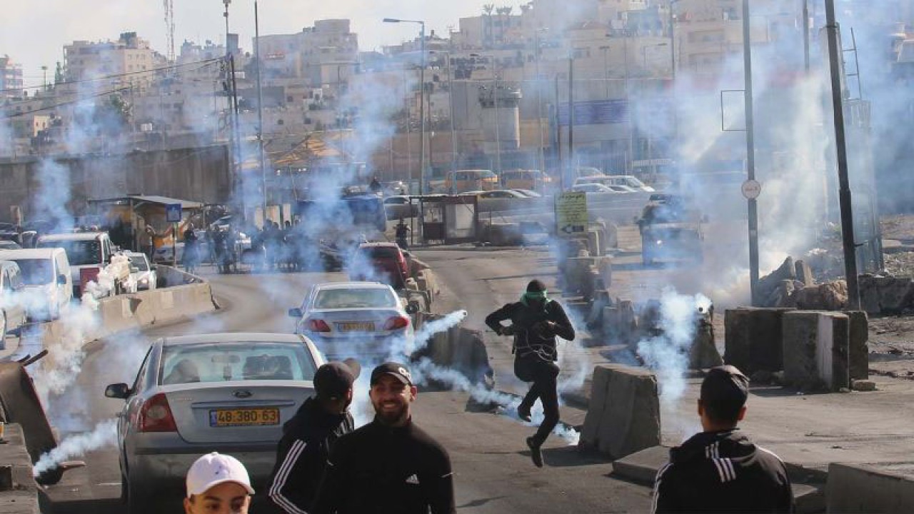 Arsip - Pengunjuk rasa Palestina berlarian untuk berlindung dari tabung gas air mata yang ditembakkan pasukan keamanan Israel dalam bentrokan di pos pemeriksaan Qalandia di dekat Kota Ramallah di Tepi Barat (27/12/2022). ANTARA FOTO/Xinhua/Nidal Eshtayeh/aww.