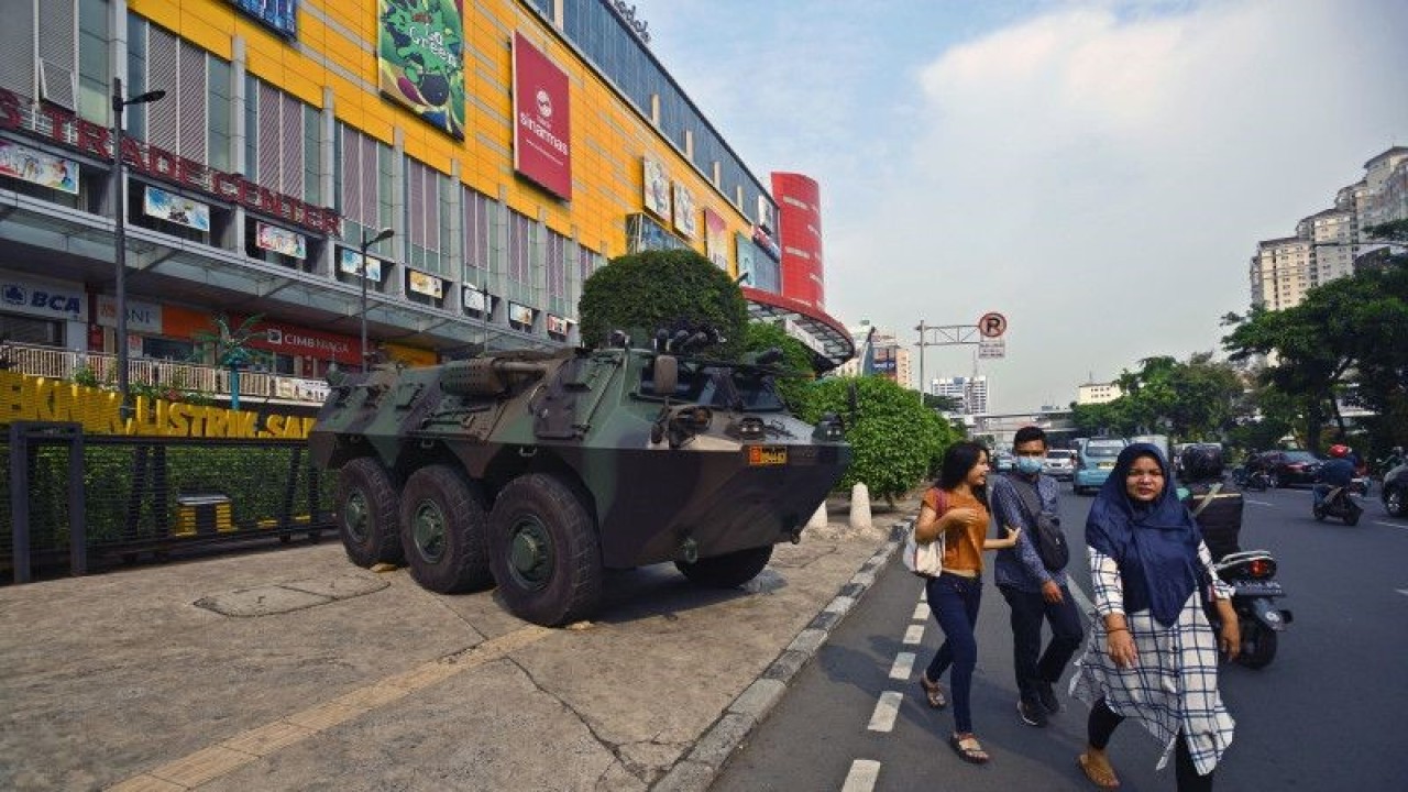 Sejumlah warga melintas di dekat kendaraan taktis Panser Anoa milik TNI yang disiagakan di depan salah satu pusat perbelanjaan di Glodok, Jakarta Barat, Jumat (14/6/2019). ANTARA FOTO/Aditya Pradana Putra/wsj. (ANTARA FOTO/ADITYA PRADANA PUTRA)