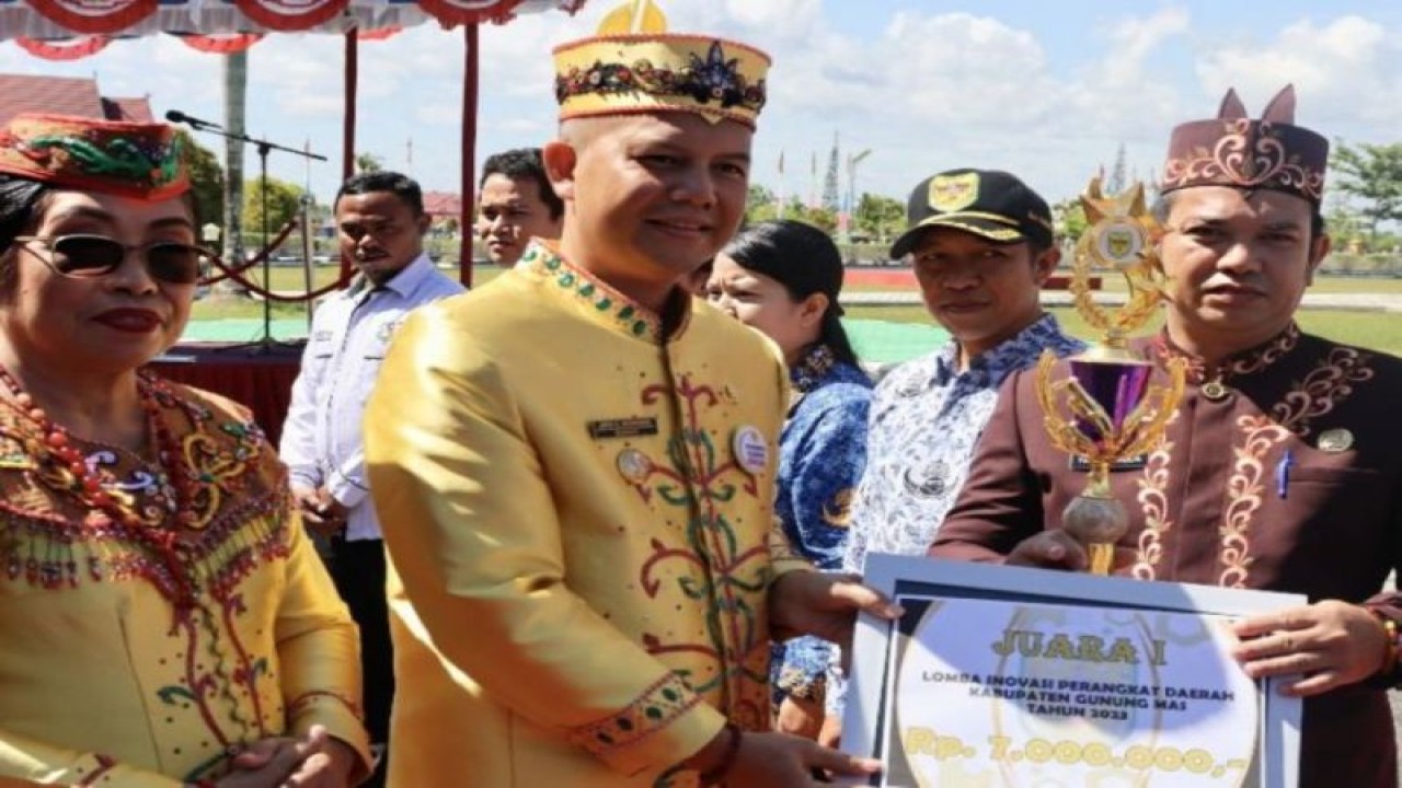 Bupati Gunung Mas Jaya S Monong (tengah) didampingi Wakil Bupati Efrensia LP Umbing menyerahkan piala dan hadiah lomba inovasi perangkat daerah kepada Kepala Bappedalitbang Yantrio Aulia di Kuala Kurun. (ANTARA/HO-Diskominfosantik Gunung Mas)