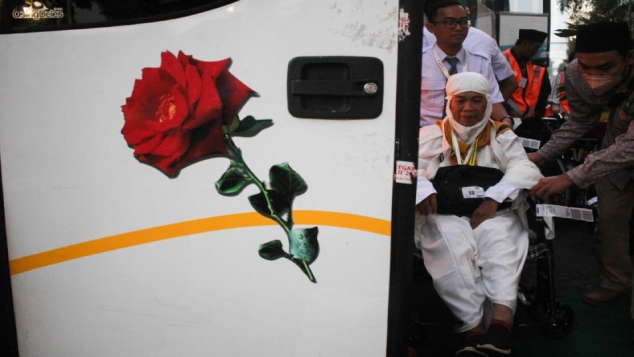 Petugas membantu seorang calon haji naik ke atas bus jelang keberangkatan ke Tanah Suci di Asrama Haji Embarkasi Surabaya. (ANTARA/Didik Suhartono)