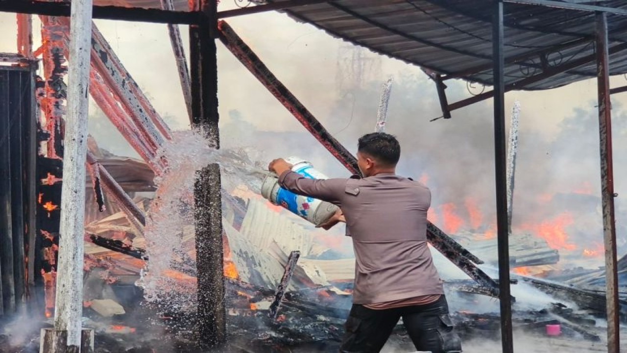 Anggota Polres Asmat saat memadamkan api dengan alat seadanya pada peristiwa kebakaran sembilan ruko di Distrik Agats, Kabupaten Asmat, Selasa (6/6/2023). ANTARA/HO-Humas Polda Papua.
