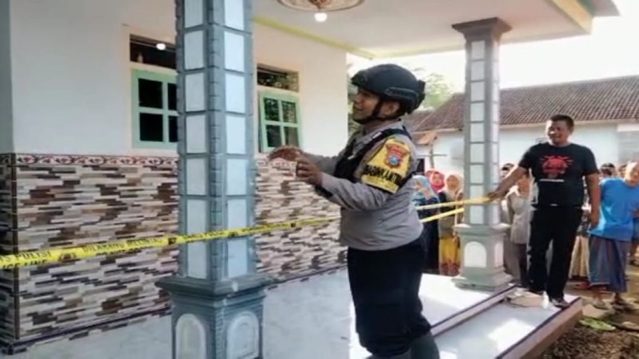 Petugas memasang garis polisi di sebuah rumah yang menjadi lokasi pembunuhan yang dilakukan ibu kepada anak kandungnya di Desa Harjomulyo, Kecamatan Silo, Kabupaten Jember, Jumat (9/6/2023). (ANTARA/HO-Polsek Sempolan)