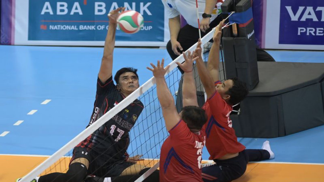Pevoli Indonesia Cahyana (kiri melakukan spike dan berusaha diblok pevoli Kamboja Tong Ravy (tengah) dan Kao Hoeurn (kanan) pada semifinal voli duduk putra ASEAN Para Games 2023 di Morodok Techo National Stadium, Phnom Penh, Kamboja, Rabu (7/6/2023). Indonesia berhasil melaju ke final setelah mengalahkan Kamboja dengan skor 3-2 (26-24. 25-22, 18-25, 18-25, 15-13). ANTARA FOTO/Zabur Karuru/tom. (ANTARA FOTO/ZABUR_KARURU)