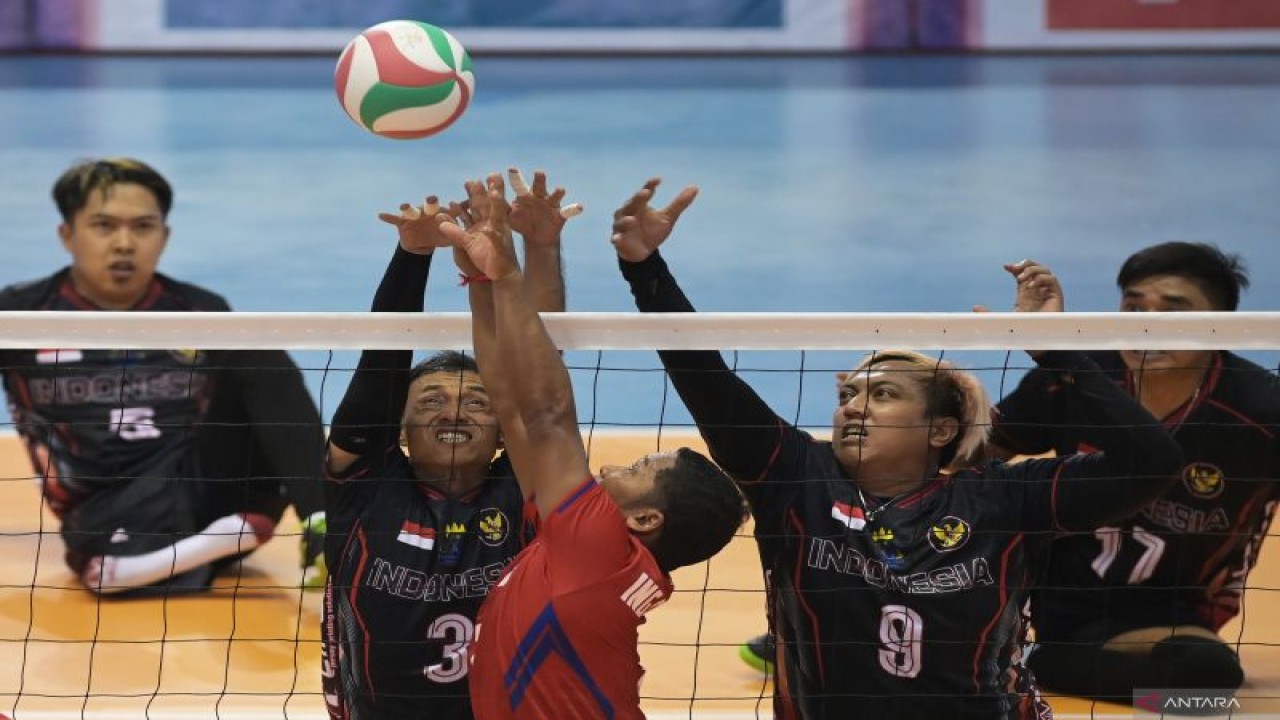 Pevoli Indonesia Purwadi (kiri) dan Murdiyan (kanan) berusaha memblok bola dari pevoli Kamboja Ing Phiream (tengah) pada semifinal voli duduk putra ASEAN Para Games 2023 di Morodok Techo National Stadium, Phnom Penh, Kamboja, Rabu (7/6/2023). (ANTARA FOTO/ZABUR_KARURU)