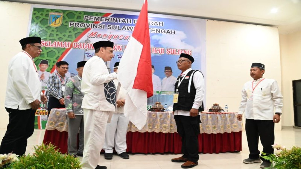Wakil Gubernur Sulteng Ma'mun Amir menyerahkan pataka kepada ketua kloter jamaah haji, dalam pelepasan pemberangkatan jamaah haji kloter pertama dari Sulteng. (ANTARA/HO-Prokopim Setda Pemprov Sulteng)