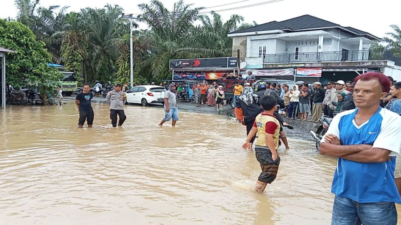 Air Sungai Batang Saman Kabupaten Pasaman Barat, Sumatera Barat meluap hingga menutupi badan jalan nasional mengakibatkan akses transportasi Simpang Empat-Ujung Gading terputus, Jumat. Antara/Altas Maulana.