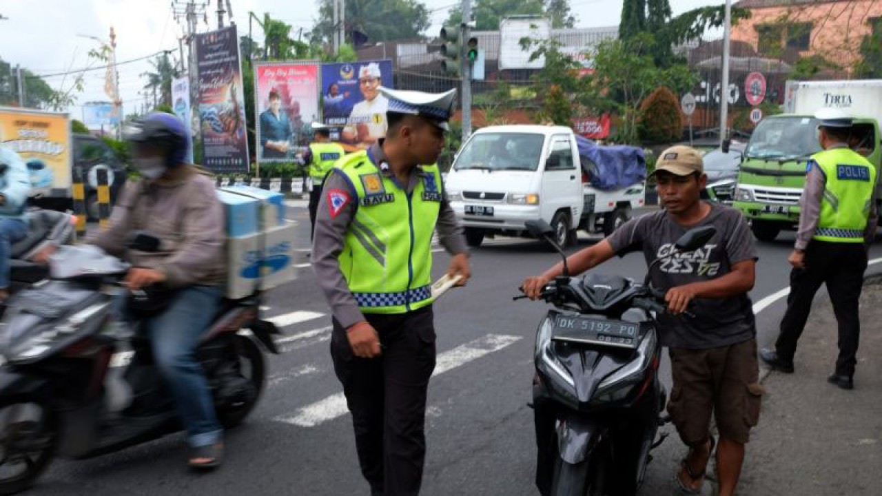 Anggota Direktorat Lalu Lintas Kepolisian Daerah Bali menindak seorang warga yang tidak menggunakan helm di sebuah ruas jalan Denpasar, Bali. ANTARA/Rolandus Nampu