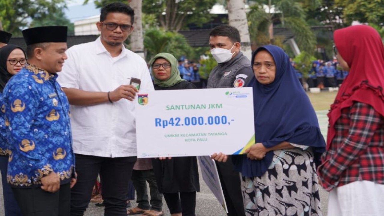 Kepala BPJAMSOSTEK Cabang Sulawesi Tengah, Lubis Latif (ke dua kiri) didampingi Wali Kota Palu, Hadianto Rasyid (kiri) menyerahkan santunan Jaminan Kematian (JKM) kepada ahli waris salah satu peserta BPJAMSOSTEK yang didaftarkan Pemerintah Kota Palu di halaman Sekretariat Daerah setempat, di Palu, Senin (17/7/2023). ANTARA/HO-BPJAMSOSTEK Cabang Sulteng