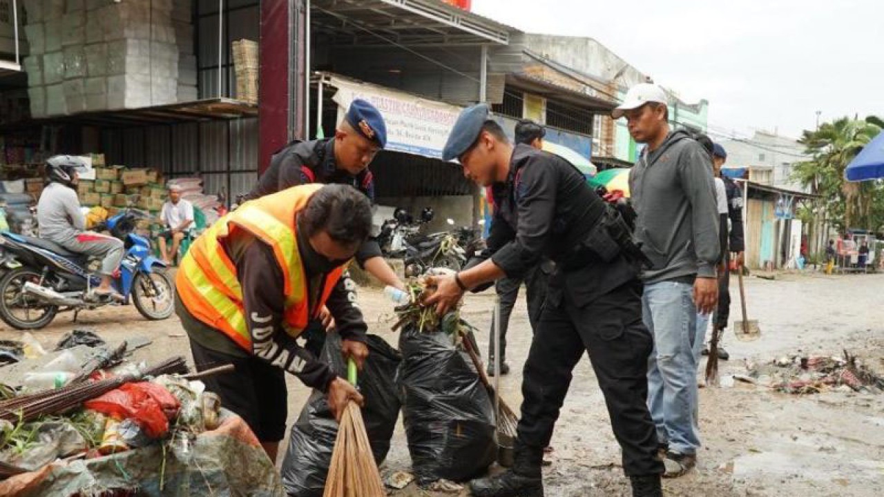 Personel Sat Brimob Polda Sultra bersama masyrakat saat membersihkan sampah di Pasar Baruga, Kota Kendari. (Antara/La Ode Muh Deden Saputra)