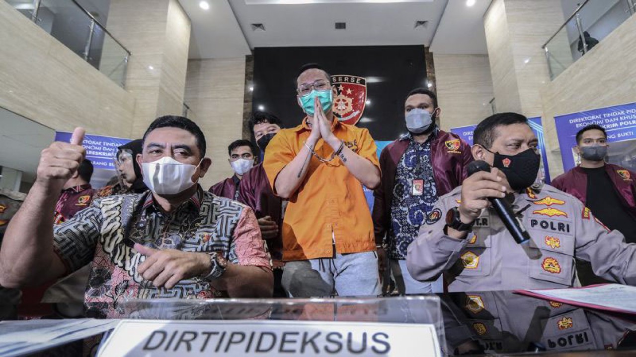 Dirtipideksus Bareskrim Polri Brigjen Whisnu Hermawan (kiri) bersama Kabag Penum Divisi Humas Polri Kombes Pol Gatot Repli Handoko (kanan) memberikan keterangan kepada media saat gelar barang bukti kasus afiliator Binomo dengan Tersangka Indra Kesuma atau Indra Kenz (tengah) di Bareskrim, Mabes Polri, Jumat (25/3/2022). Dalam acara tersebut petugas kepolisian menghadirkan sejumlah barang bukti berupa uang sejumlah Rp1,24 miliar serta mobil Tesla Model 3. ANTARA FOTO/Adam Barik/rwa.