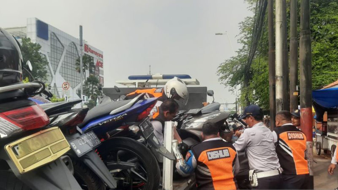 Petugas Dinas Perhubungan DKI Jakarta mengangkut belasan motor yang parkir liar di trotoar di Jalan Matraman Raya, Jatinegara, Jakarta Timur, Kamis (13/7/2023). (ANTARA/Syaiful Hakim)
