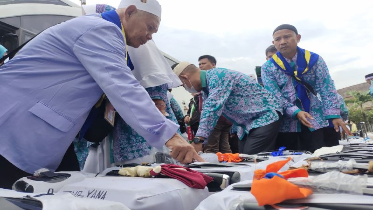 Jamaah haji yang baru kembali dari Tanah Suci mengambil koper mereka setelah tiba di asrama haji di Kota Bandar Lampung, Provinsi Lampung, Rabu (5/7/2023). (ANTARA/Dian Hadiyatna)