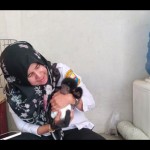 Kepala Unit Pelaksana Teknis Dinas (UPTD) Taman Rimba Jambi Erliani menggendong bayi siamang.(ANTARA/Thaliqah)-1688375021
