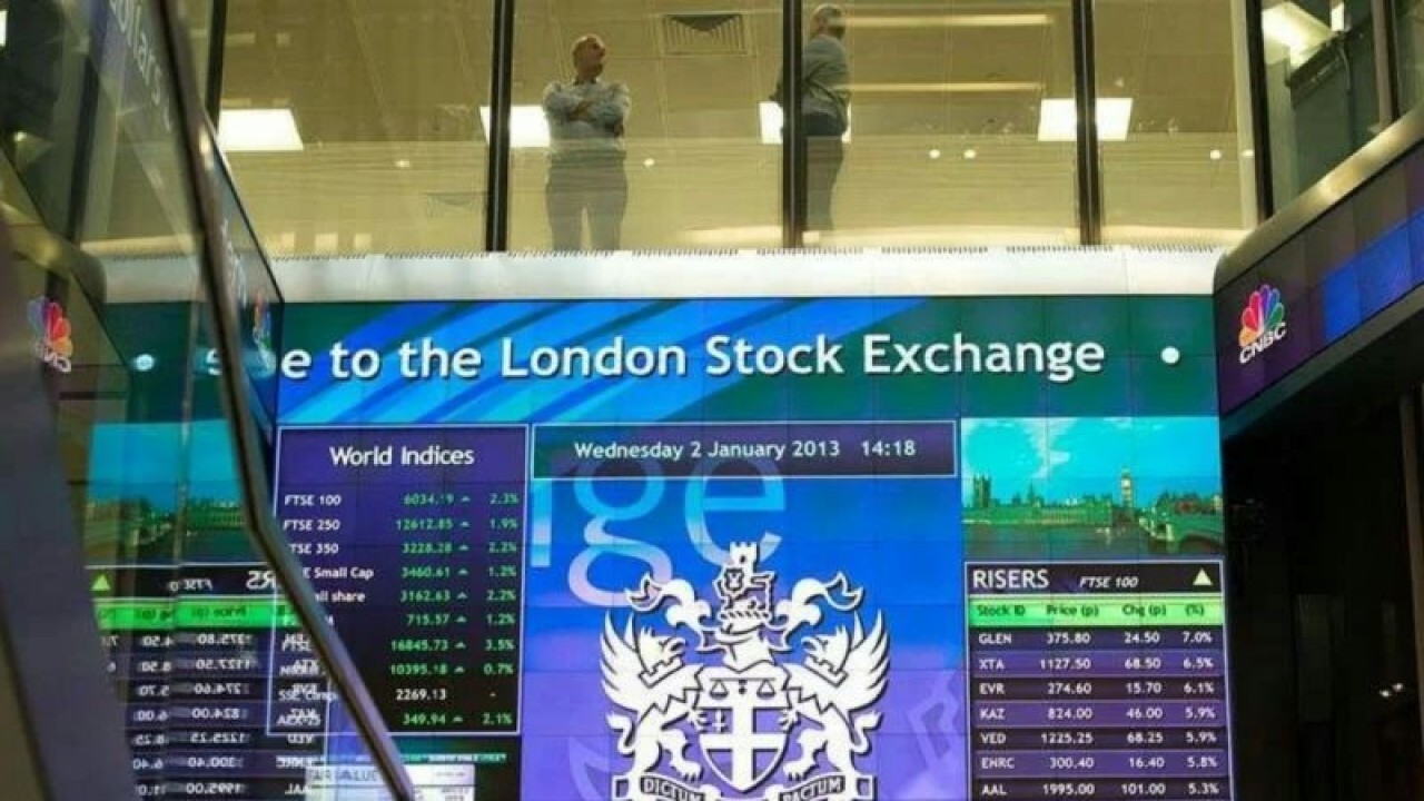 Pekerja terlihat berbincang di atas papan elektronik pergerakan saham di London Stock Exchange, Inggris. (REUTERS/Paul Hackett/aa.)