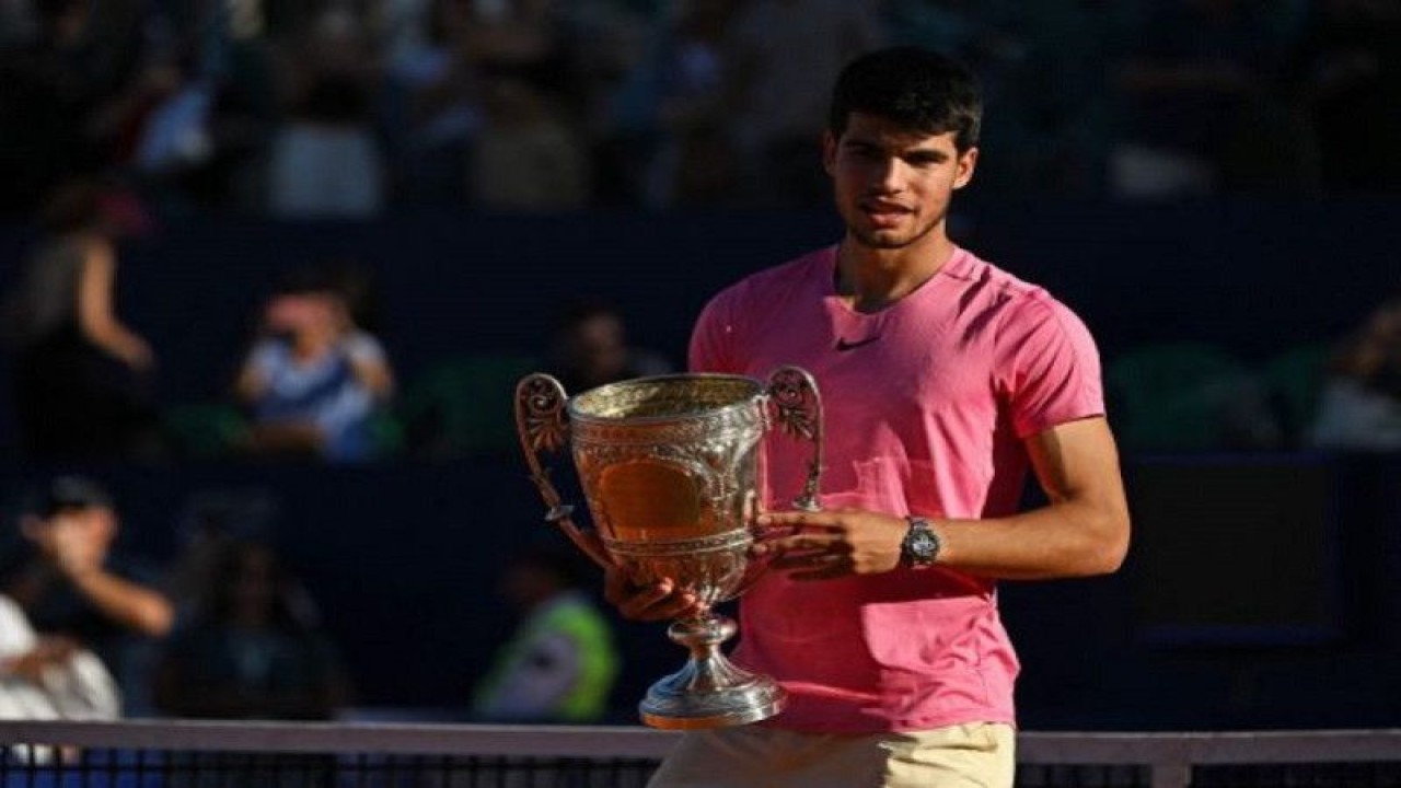 Petenis Spanyol Carlos Alcaraz menggenggam trofi setelah menjuarai turnamen Argentina Open dengan mengalahkan Cameron Norrie asal Inggris pada final di Buenos Aires, Argentina, Minggu (19/2/2023) (AFP/LUIS ROBAYO)