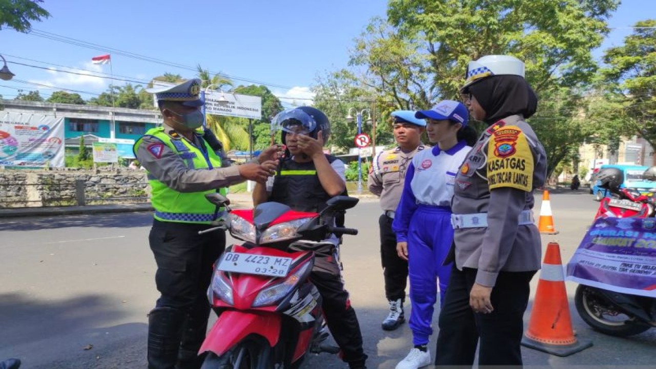 Petugas polisi dan karyawan DAW saat membagikan helm gratis kepada pengendara roda dua, di Tikala, Manado, Jumat (21/7/2023). ANTARA/Nancy L Tigauw.