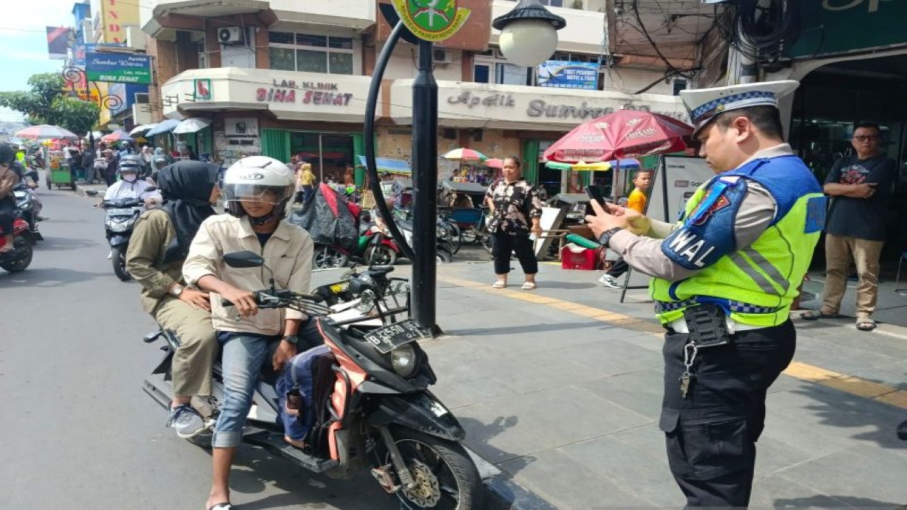Personel Satlantas Polres Sukabumi Kota saat menjatuhkan sanksi tilang elektronik (ETLE) kepada pengendara sepeda motor yang penumpangnya tidak menggunakan helm di Jalan Ahmad Yani, Kota Sukabumi, Jabar pada Operasi Patuh Lodaya 2023. Antara/Aditya Rohman.