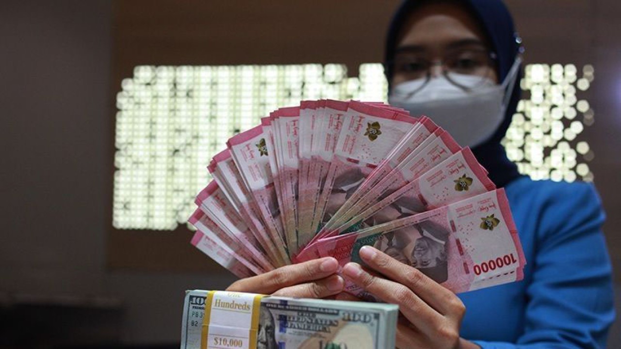 Ilustrasi - Petugas perbankan menunjukkan uang dolar AS dan uang rupiah. (ANTARA FOTO/Reno Esnir/tom/aa)