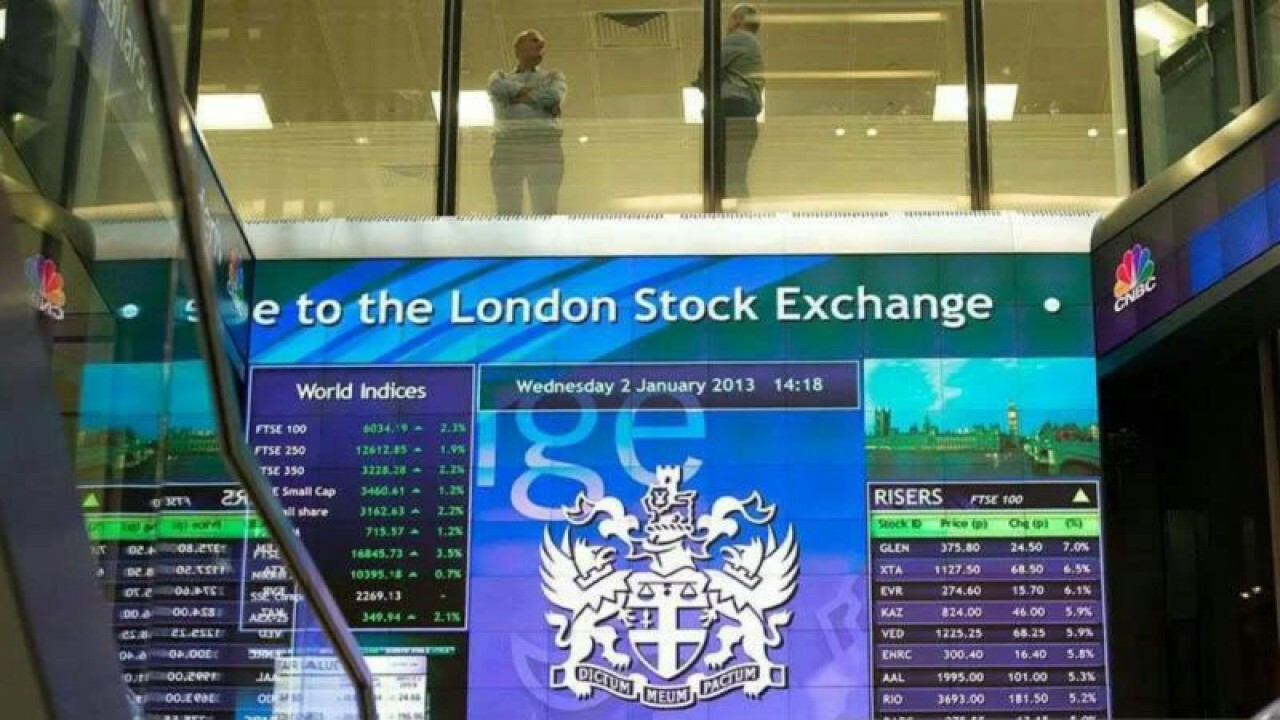 Pekerja terlihat berbincang di atas papan elektronik pergerakan saham di London Stock Exchange, Inggris. (REUTERS/Paul Hackett/aa.)