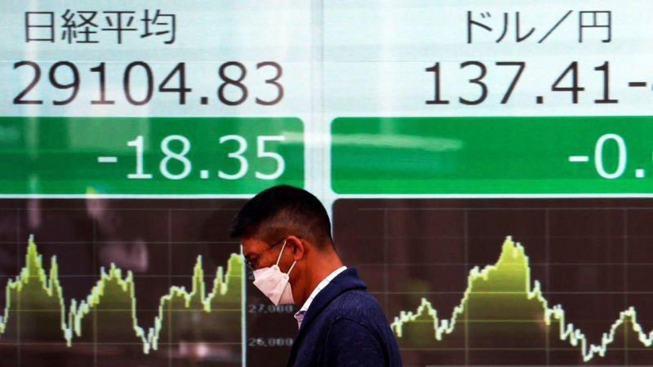 Seorang pria berjalan melewati monitor elektronik yang menampilkan rata-rata saham Nikkei dan nilai tukar yen Jepang terhadap dolar AS di luar sebuah pialang di Tokyo, Jepang, Selasa (2/5/2023). (ANTARA/REUTERS/Issei Kato/am.)