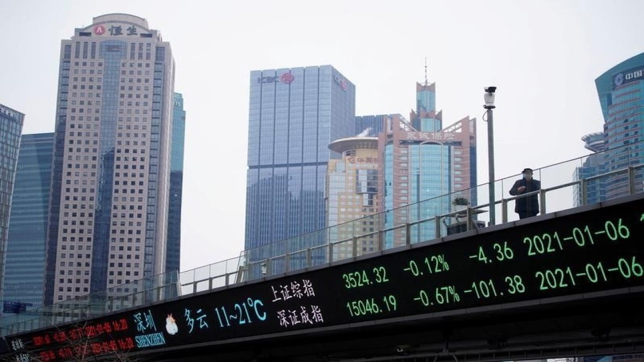 Dokumentasi - Seorang pria berdiri di jembatan penyeberangan dengan papan elektronik yang menunjukkan indeks saham Shanghai dan Shenzhen, di distrik keuangan Lujiazui di Shanghai, Cina (6/1/2021). ANTARA/REUTERS/Aly Song/am.