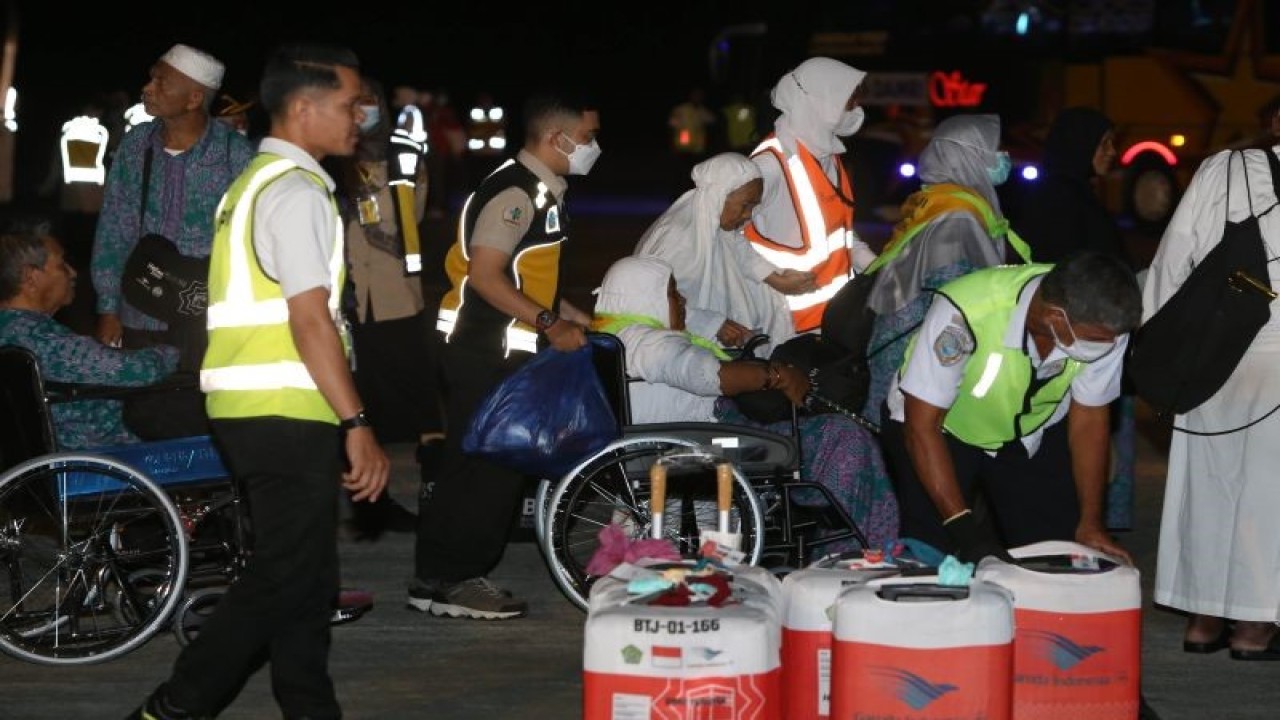 Petugas membantu jamaah haji kelompok terbang (kloter) pertama saat tiba di Bandara Internasional Sultan Iskandar Muda (SIM), Aceh Besar, Aceh, Rabu (5/7/2023). (ANTARA/Khalis Surry)