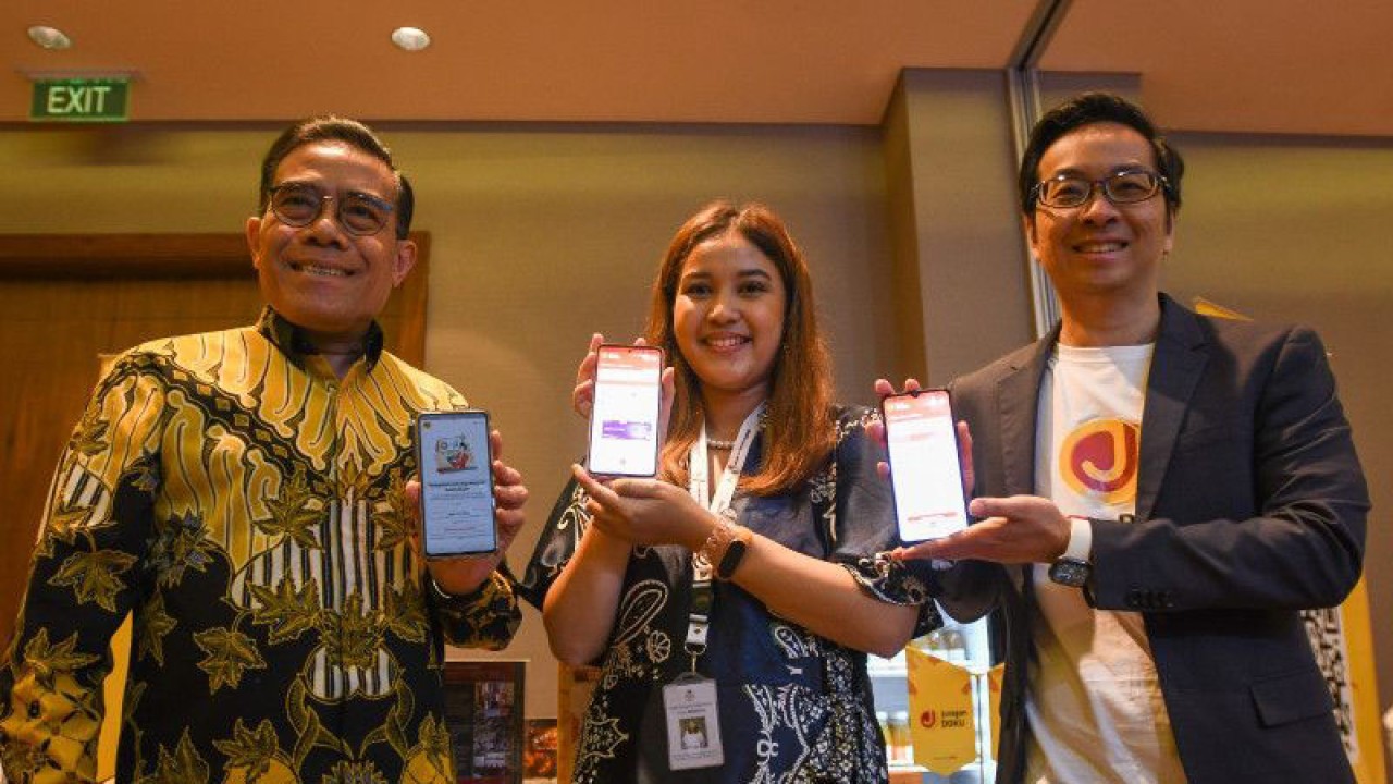 CEO DOKU Chris Yeo (kanan), Plh Deputi Bidang UKM Kemenkop UMKM Rulli Nuryanto (kiri), dan pelaku UMKM Anindwitya Rizqi Monica (tengah) menunjukkan aplikasi Juragan DOKU usai peluncuran di Jakarta, Senin (3/7/2023). ANTARA/Aditya Pradana Putra.