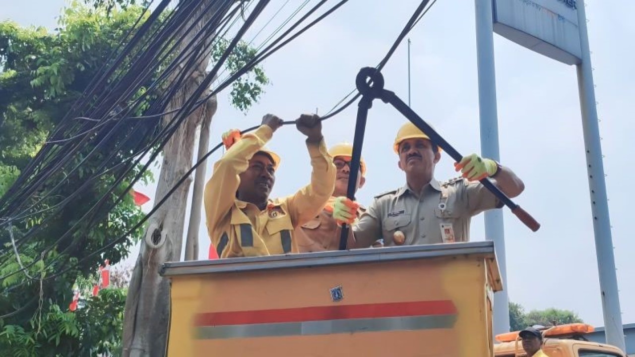 Wali Kota Administrasi Jakarta Timur Muhammad Anwar didampingi Kepala Sudin Bina Marga Jaktim Benhard Hutajulu memotong kabel udara yang menjuntai ke bawah di Jalan Raden Inten II, Duren Sawit, Jakarta Timur, Selasa (15/8/2023). ANTARA/Syaiful Hakim
