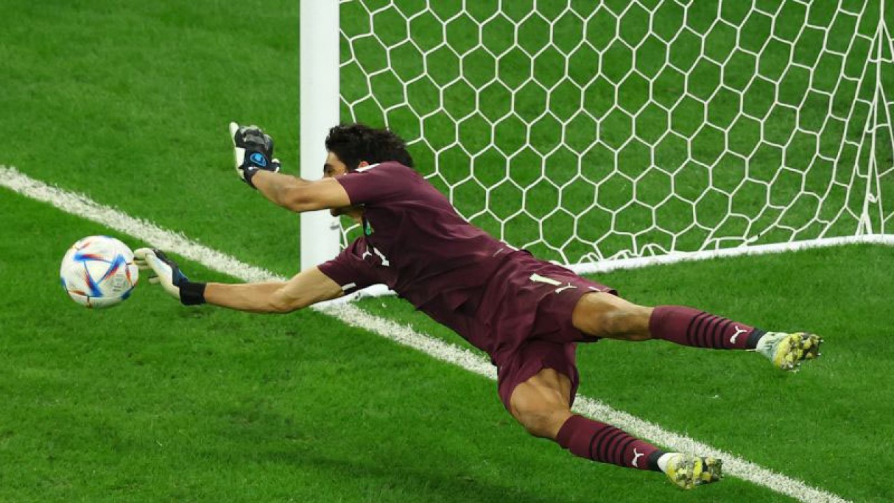 Penjaga gawang Maroko Yassine Bounou berhasil menepis tendangan pesepak bola Spanyol Sergio Busquets dari titik penalti dalam laga babak 16 besar Piala Dunia 2022, di Stadion Education City, Al Rayyan, Qatar, Selasa (6/12/2022),   Maroko berhasil melaju ke perempat final setelah kalahkan Spanyol 3-0 lewat adu penalti​​​​​​​. ANTARA FOTO/Reuters-Lee Smith/hp.