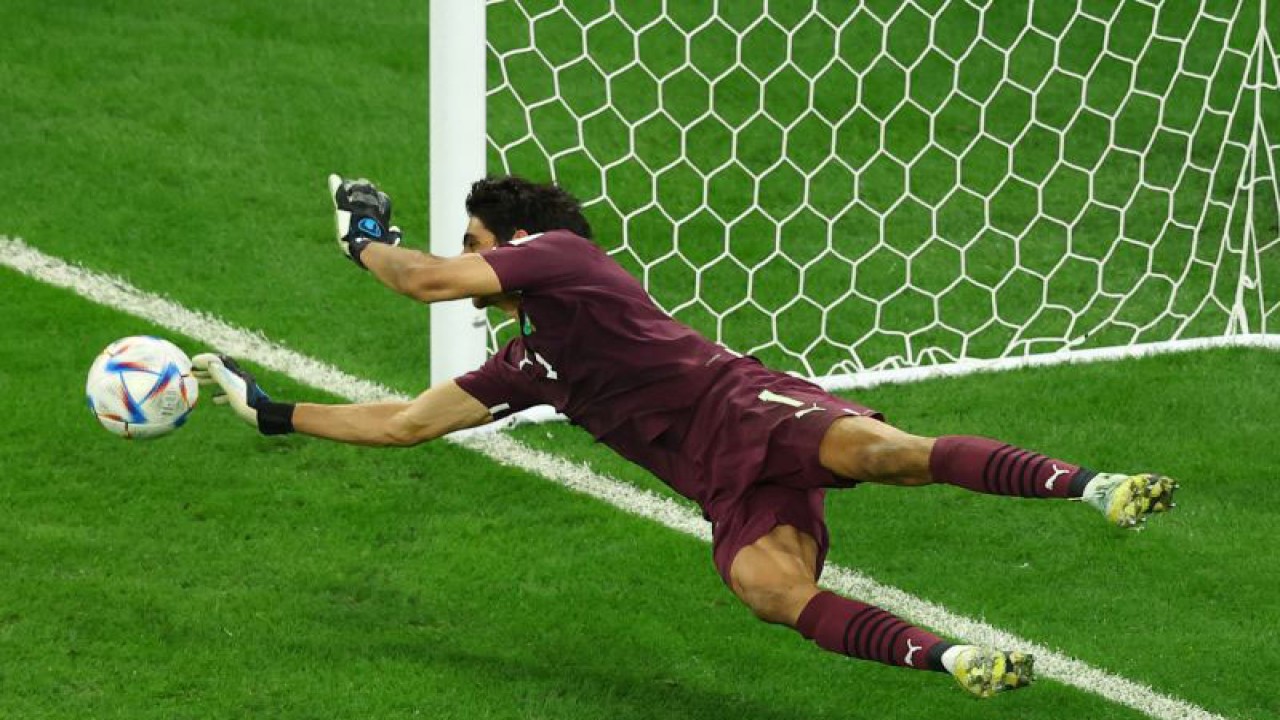 Penjaga gawang Maroko Yassine Bounou berhasil menepis tendangan pesepak bola Spanyol Sergio Busquets dari titik penalti dalam laga babak 16 besar Piala Dunia 2022, di Stadion Education City, Al Rayyan, Qatar, Selasa (6/12/2022),   Maroko berhasil melaju ke perempat final setelah kalahkan Spanyol 3-0 lewat adu penalti​​​​​​​. ANTARA FOTO/Reuters-Lee Smith/hp.