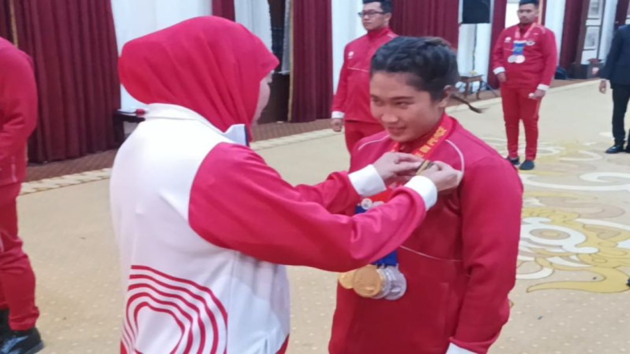 Gubernur Jatim Khofifah Indar Parwansa menyematkan lencana "Jer Basuki Mawa Beya" kepada atlet para renang Mutiara Cantik Harsanto di Gedung Negara Grahadi Surabaya, Jumat (18/8/2023). (ANTARA/Hanif Nashrullah)