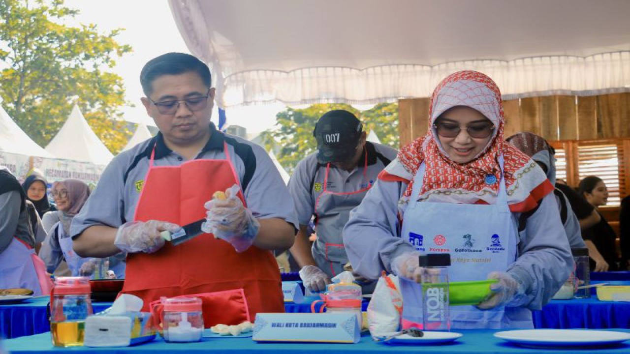 Wali Kota Banjarmasin Ibnu Sina dan Ketua TP PKK Banjarmasin Siti Wasilah mengikuti lomba memasak pada kegiatan Festival UMKM 2023 di Taman Kamboja, Kota Banjarmasin, Kalimantan Selatan, Jumat (18/8/2023). (ANTARA/Tumpal Andani Aritonang)