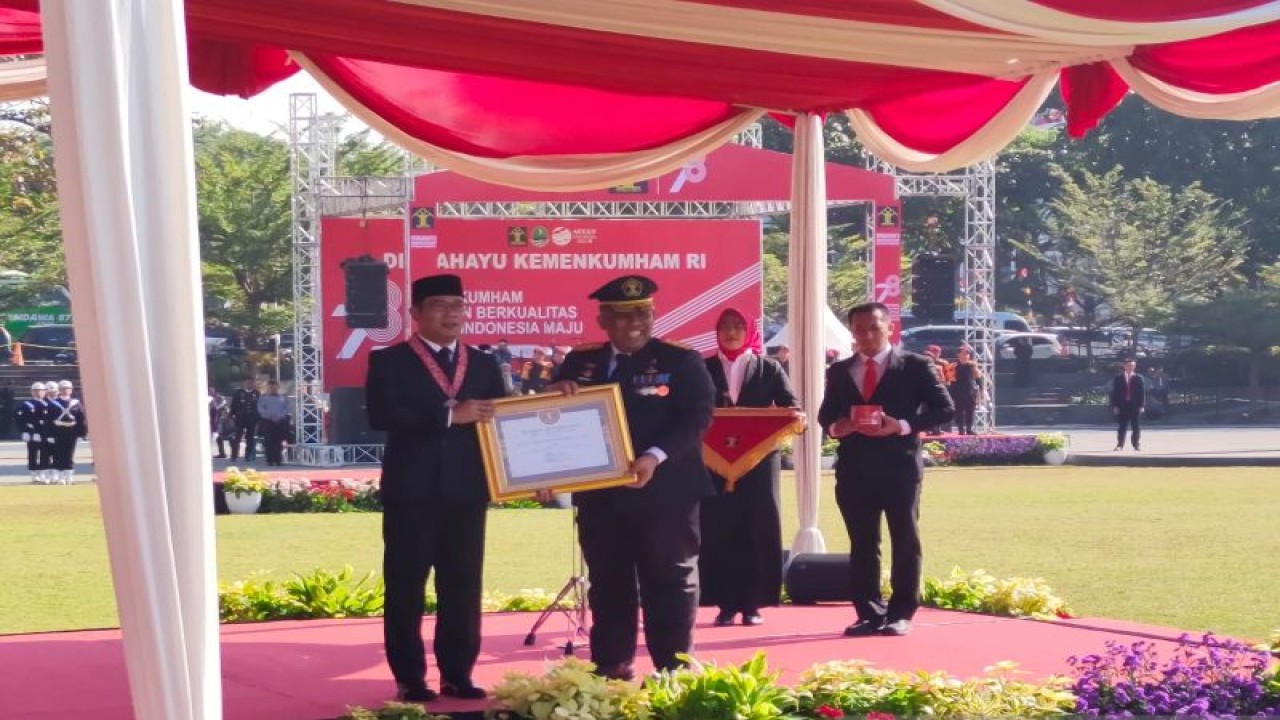 Kepala Kantor Wilayah Kementerian Hukum dan HAM (Kanwil Kemenkumham) Jawa Barat R Andika Dwi Prasetya (kanan) memberikan piagam penghargaan pada Gubernur Jawa Barat Ridwan Kamil (kiri) pada upacara Hari Dharma Karya Dhika (HDKD) Kemenkumham ke-78 di Lapangan Gasibu, Bandung, Senin (21/8/2023). ANTARA/Ricky Prayoga.