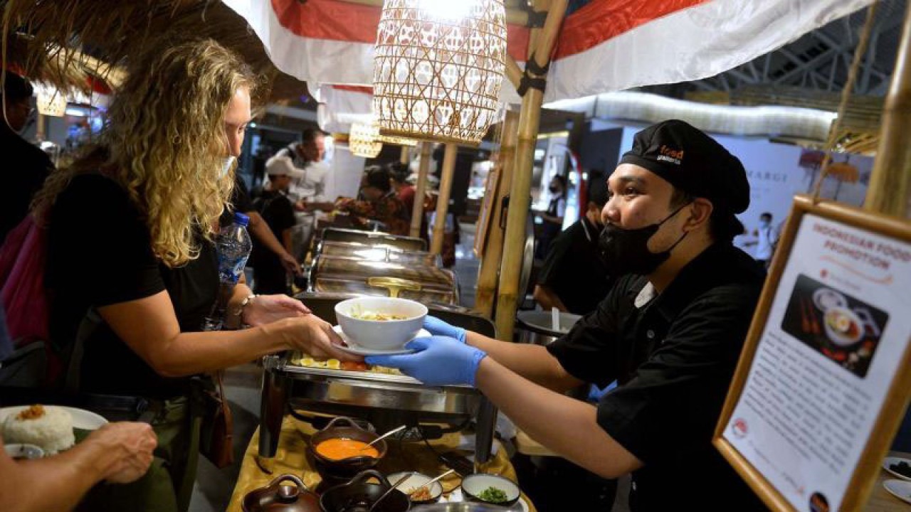 Petugas menyajikan makanan khas Indonesia di stan kegiatan Indonesia Spice Up The World di Terminal Keberangkatan Internasional Bandara Internasional I Gusti Ngurah Rai, Badung, Bali, Rabu (17/8/2022). Kegiatan lintas kementerian/lembaga dilakukan sebagai salah satu upaya untuk mempromosikan dan meningkatkan pemasaran produk bumbu atau pangan olahan serta rempah khas Indonesia kepada dunia. ANTARA FOTO/Fikri Yusuf/aww.