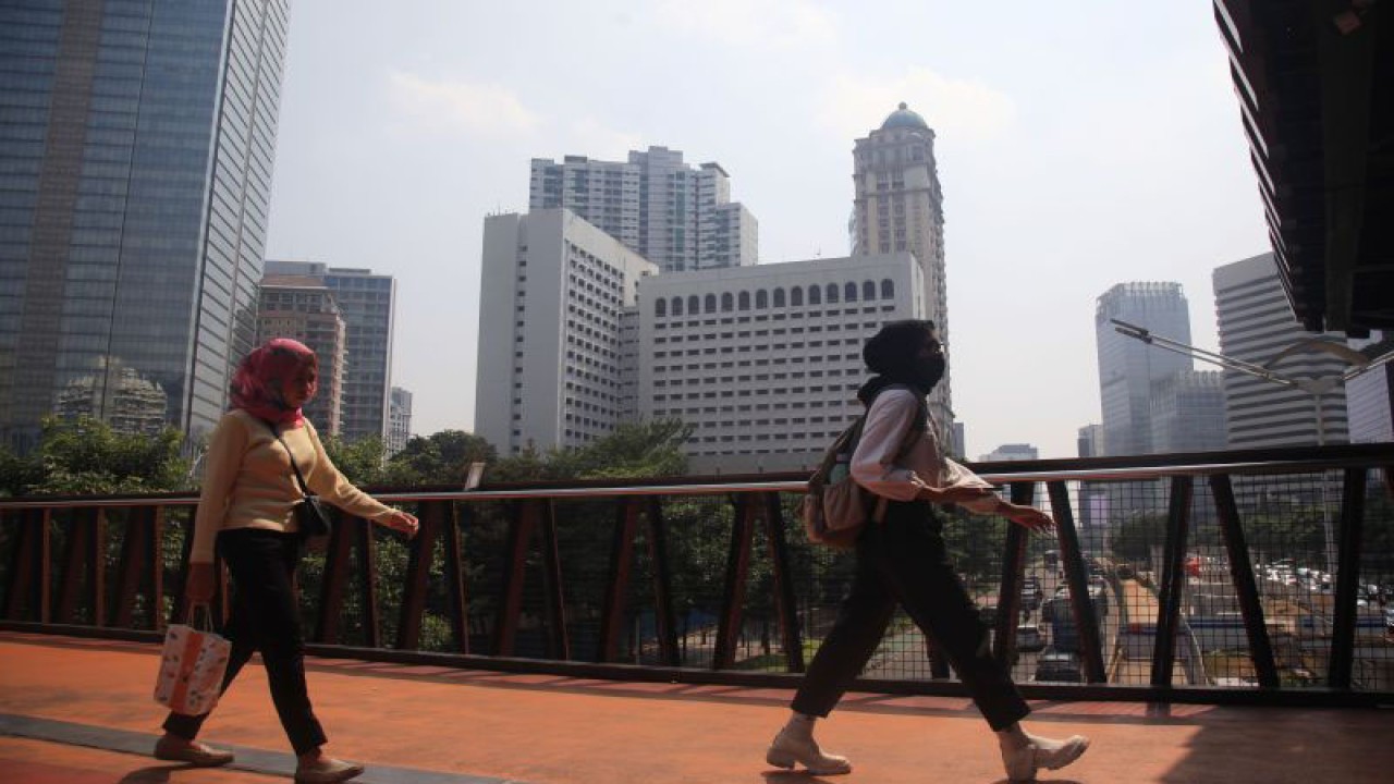 Warga melintas memakai masker untuk melindungi diri dari debu, di Jembatan Penyeberangan Sepeda (JPS) sekaligus Jembatan Penyeberangan Orang (JPO) di Jalan Sudirman, Jakarta, Selasa (8/8/2023). (ANTARA FOTO/Reno Esnir/hp)