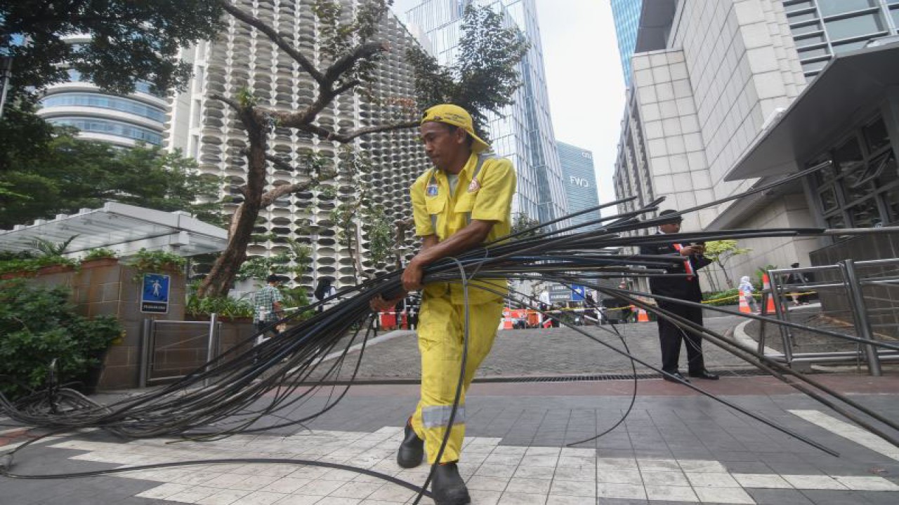 Petugas Dinas Bina Marga DKI Jakarta merapikan kabel utilitas yang telah dipotong di Jalan Jenderal Sudirman, Jakarta, Selasa (9/5/2023). ANTARA FOTO/Indrianto Eko Suwarso/YU