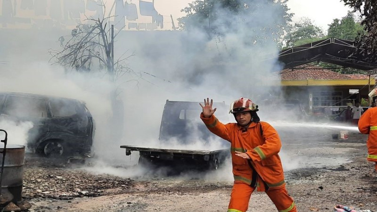 Petugas pemadam saat melakukan proses pemadaman terhadap tiga unit kendaraan mobil. (Azmi Samsul Maarif)
