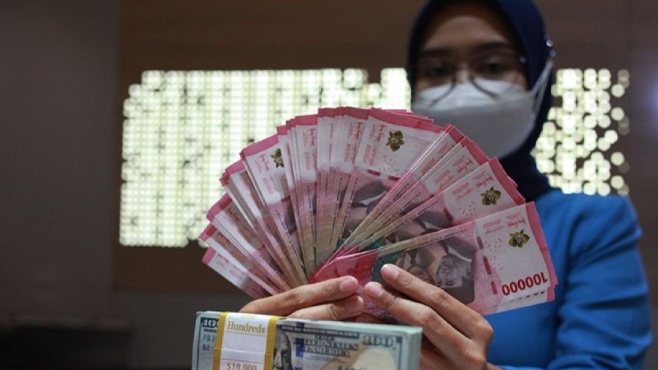 Petugas perbankan menunjukkan uang dolar AS dan uang rupiah, Jakarta, Selasa (31/1/2023). (ANTARA FOTO/Reno Esnir/tom/aa)