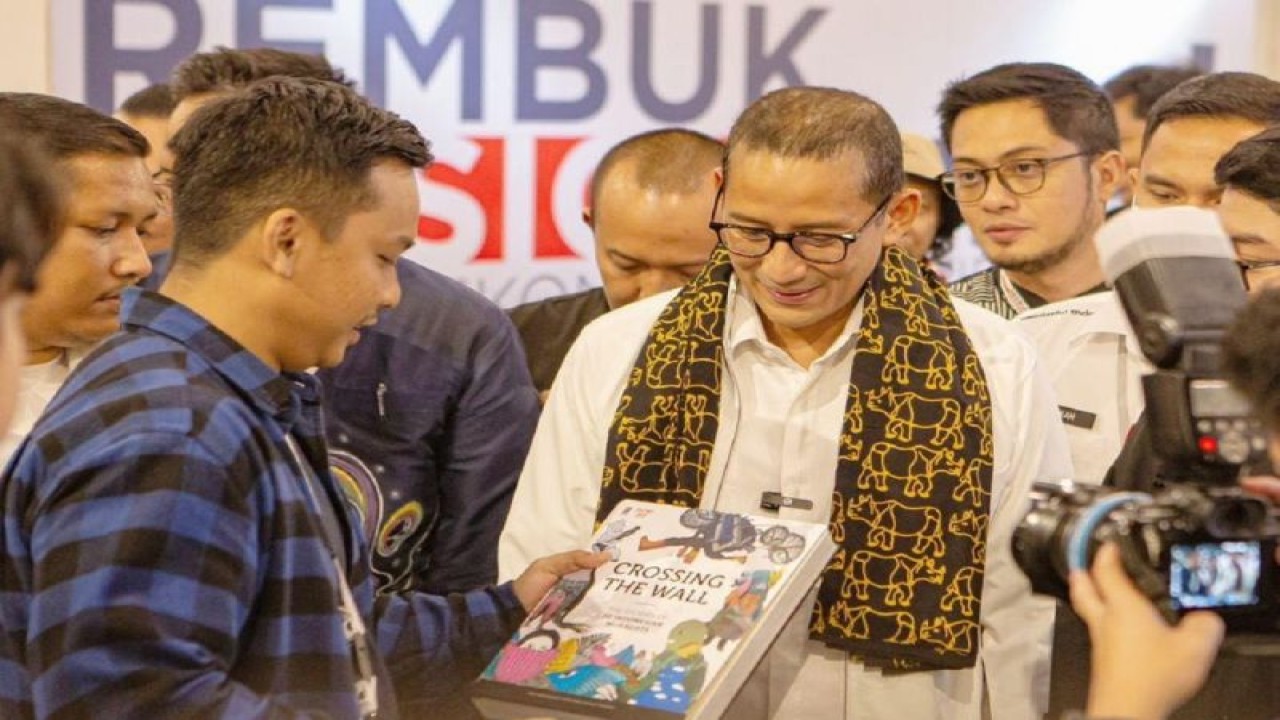 Menteri Pariwisata dan Ekonomi Kreatif (Menparekraf) Sandiaga Uno saat berbincang dengan salah satu penulis buku "Crossing The Wall: The Stories of 20 Indonesian Muralists" saat peluncuran buku yang mengangkat seniman mural tanah air di Jakarta, Selasa (15/8/2023) (Antara/HO/Mowilex)