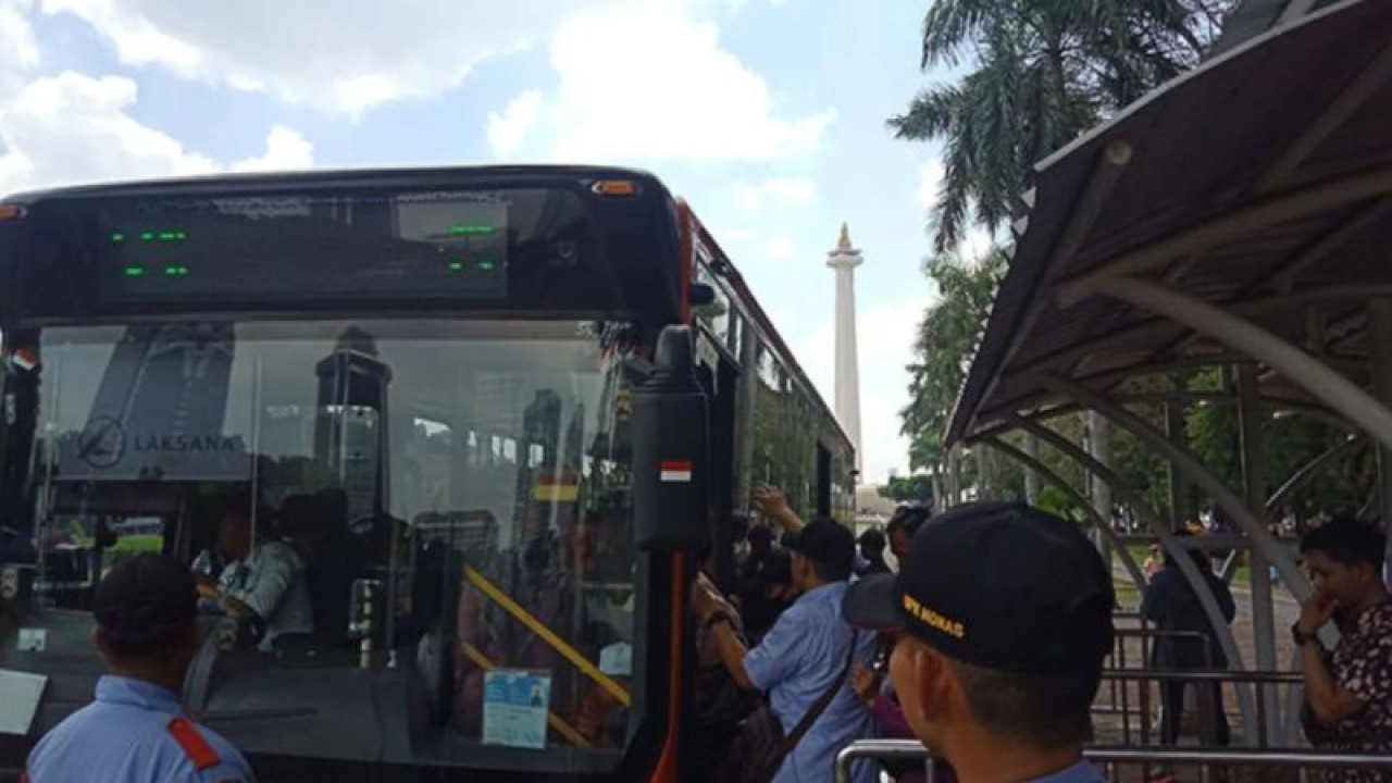 Pengunjung Monas sedang memasuki bus Transjakarta yang berhenti untuk menurunkan dan menjemput pengunjung di bagian depan pintu lenggang Kawasan Monas, Jakarta Pusat, Minggu (23/4/2023). ANTARA/Redemptus Elyonai Risky Syukur/aa