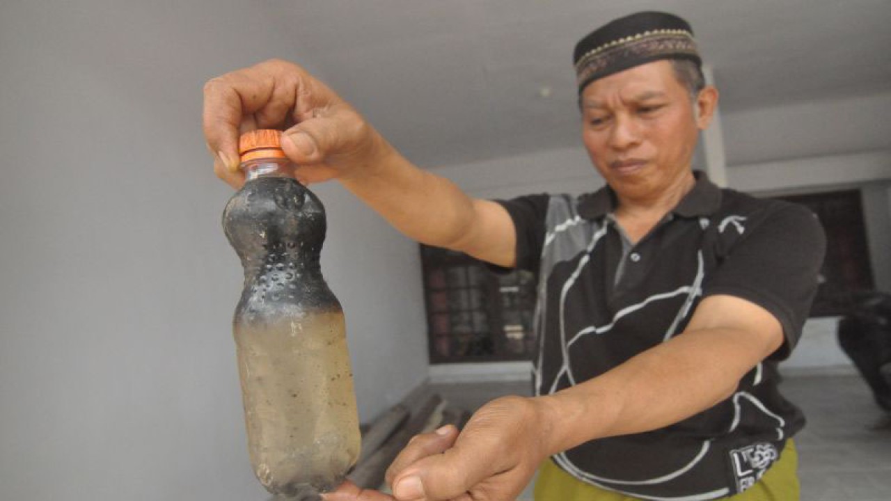 Warga menunjukkan botol yang berisi air yang diduga tercemar bahan bakar minyak (BBM) di Kelurahan Pasar Kepahiang, Kabupaten Kepahiang, Provinsi Bengkulu, Senin (11/9/2023). Sebanyak 20 sumur air milik warga setempat diduga tercemar BBM sehingga airnya tidak dapat dikonsumsi. ANTARA FOTO/Muhammad Izfaldi/aww. (ANTARA FOTO/MUHAMMAD IZFALDI)