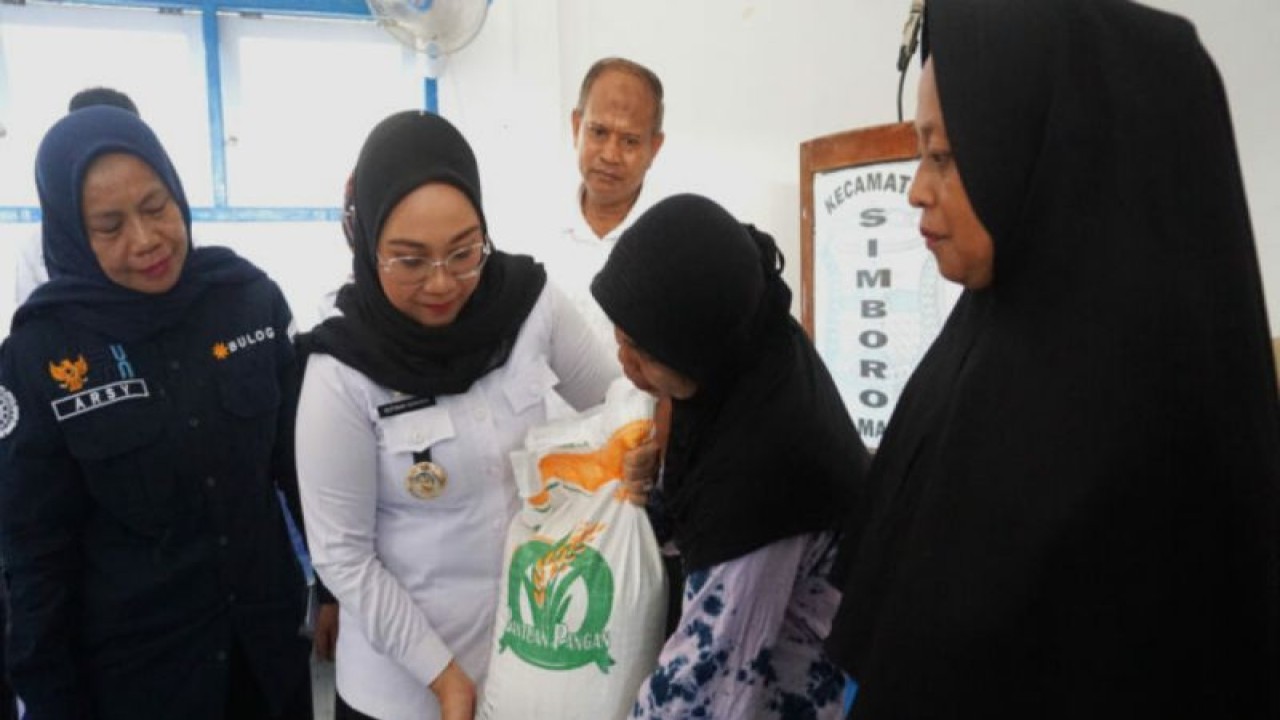 Bupati Mamuju Sutinah Suhardi (dua dari kiri) saat menyerahkan secara simbolis bantuan beras Cadangan Pangan Pemerintah (CPP) kepada salah seorang penerima manfaat. (ANTARA/HO/Humas Pemkab Mamuju)